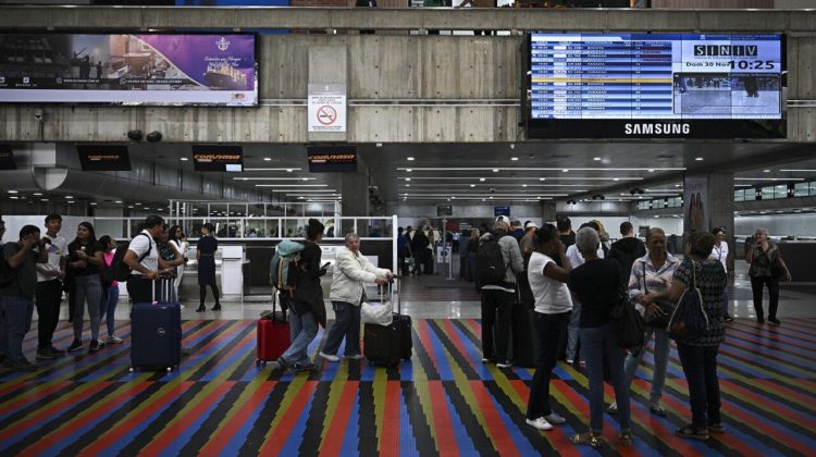 Passengers queue at a counter at the Simon Bolivar International Airport in Maiquetia, La Guaira State, Venezuela, on November 30, 2025. US President Donald Trump sharply escalated his threats against Venezuela on Saturday with an ominous warning that the country's airspace should be considered "closed," raising fears of imminent military action. (Photo by Federico PARRA / AFP)