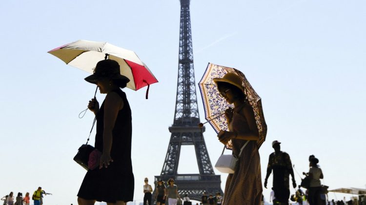 (FILES) In this file photo taken on August 03, 2018  tourists use umbrellas to shelter from the sun as they walk at Esplanade du Trocadero in front of The Eiffel Tower in Paris. - The Eiffel Tower will reopen on July 16, 2021, after several months of closure due to the coronavirus pandemic, the Paris landmark's operator said on July 15, 2021, with a limited number of 10,000 a day to meet distancing requirements. (Photo by ALAIN JOCARD / AFP)
