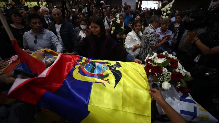 AME9921. QUITO (ECUADOR), 11/08/2023.- Simpatizantes colocan una bandera nacional sobre el féretro del candidato Fernando Villavicencio, durante un velatorio público en el Centro de Exposiciones hoy, en Quito (Ecuador). El féretro de Villavicencio, el candidato a la Presidencia de Ecuador asesinado el miércoles, salió del cementerio al que había sido trasladado para tener un breve velatorio público antes de regresar al camposanto y proceder con su inhumación. Los simpatizantes tuvieron la oportunidad de dar el último adiós a Villavicencio después de que llegaran hasta los exteriores del tanatorio y luego del cementerio para insistir en que se celebrara un velatorio público. EFE/ José Jácome