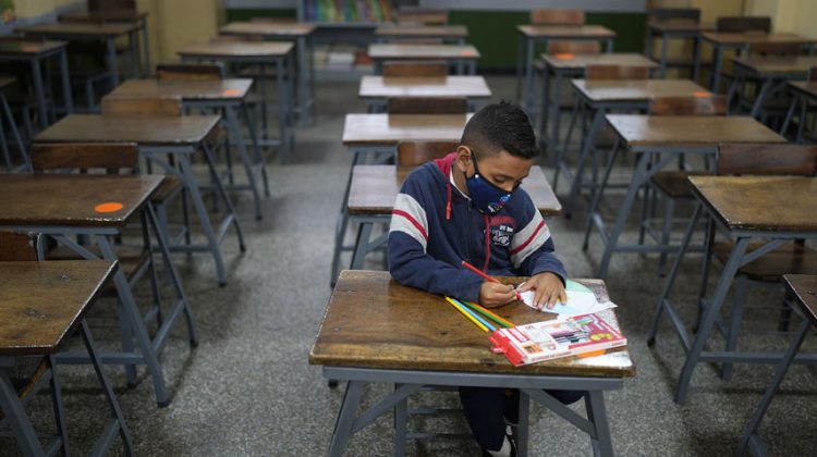 Sebastián, de 7 años, asiste solo a la clase de matemáticas el primer día de regreso a la escuela presencial desde el inicio de las restricciones pandémicas de COVID-19 en la escuela municipal Andrés Bello en Caracas, Venezuela, el lunes 25 de octubre de 2021. Foto AP / Ariana Cubillos