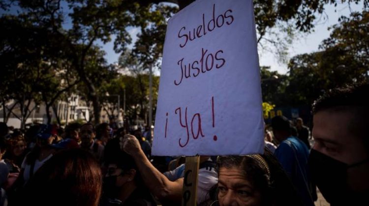 AME5609. CARACAS (VENEZUELA), 11/01/2023.- Un grupo de personas gritan consignas durante una manifestación por mejoras salariales, hoy, en Caracas (Venezuela). Miles de trabajadores públicos y jubilados de Venezuela marcharon este miércoles en el centro de Caracas para exigir un aumento en los salarios y pensiones, cuyo monto mínimo establecido por el Gobierno es de unos 7 dólares mensuales, mientras que una familia necesita 50 veces ese ingreso solo para comer. EFE/ Miguel Gutiérrez