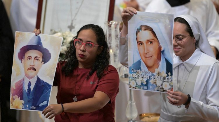 Members of the Archdiocese of Caracas show portraits of Venezuelan saints Jose Gregorio Hernandez and Mother Carmen Rendiles during a mass in honor of the late Pope Francisco in Caracas on April 26, 2025. Pope Francis was buried Saturday in the Basilica of Santa Maria Maggiore in Rome, after a crowded farewell to the pontiff who came from the end of the world and who put the underprivileged at the heart of the Catholic Church. (Photo by Juan BARRETO / AFP)