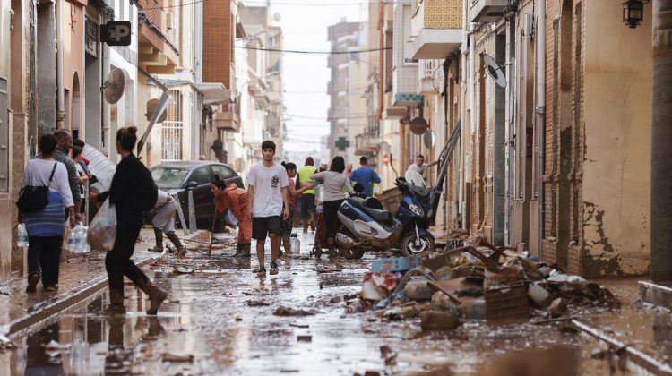 VALENCIA, 30/10/2024.- Unas personas caminan por una calle cubierta de lodo mientras otras se afanan en las labores de limpieza tras las intensas lluvias por la fuerte dana que afecta especialmente el sur y el este de la península ibérica, este miércoles en Valencia. EFE/Manuel Bruque