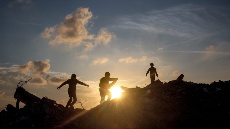 Boys walk atop a mound of rubble at a camp for people displaced by conflict in Bureij in the central Gaza Strip on January 17, 2025 following the announcement of a truce amid the ongoing war between Israel and Hamas. (Photo by Eyad BABA / AFP)