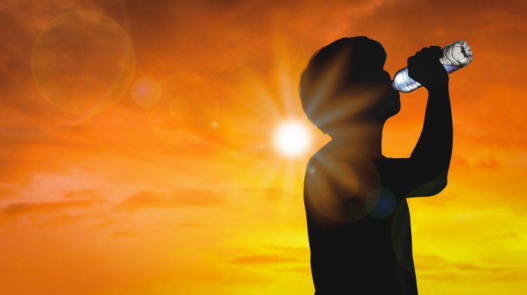 Silhouette man is drinking water bottle on hot weather background with summer season. High temperature and heat wave concept.