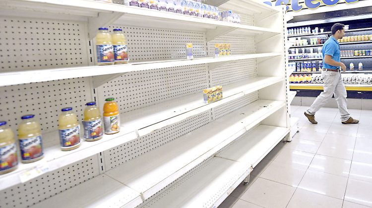A man walks next to empty shelves in a supermarket in Caracas on January 22, 2012. According to the Central Bank (BCV) shortage of goods reached 16.3% in December 2012, the highest number in the last four years. AFP PHOTO / Leo RAMIREZ