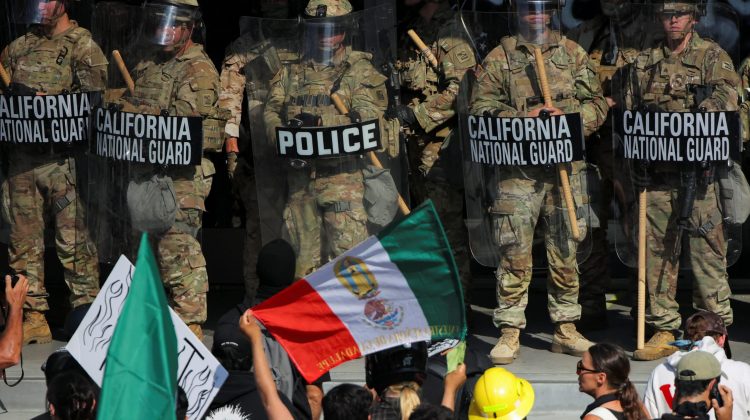 A demonstrator displays a flag in front of California National Guard troops, as protests against immigration sweeps continue, in Los Angeles, California, U.S. June 9, 2025.  REUTERS/Daniel Cole