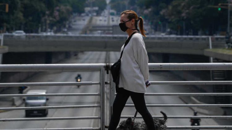A woman wearing a face mask walks her dog at Libertador Avenue in Caracas on May 14, 2020 amid the novel coronavirus (COVID-19) outbreak. - Maduro's government claims to have contained the spread of the new coronavirus in Venezuela, but maintains without changes the quarantine declared two months ago. According to analysts, the reason goes beyond the pandemic: an aggravated gasoline shortage that prevents reactivating the economy. (Photo by Federico PARRA / AFP)