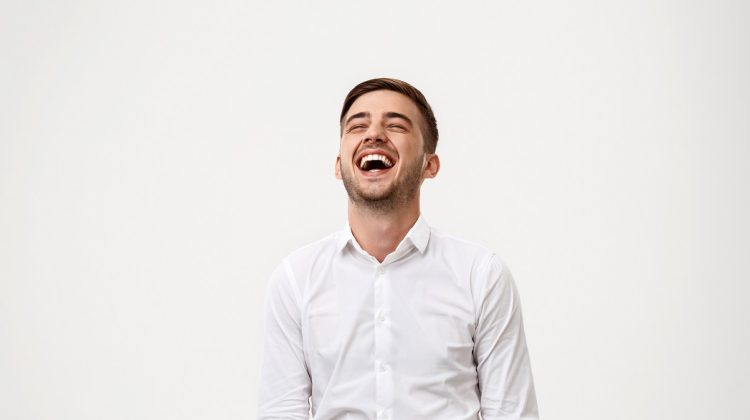 Young successful businessman smiling, laughing over white background. Copy space.