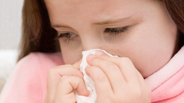 Girl blowing her nose --- Image by © Royalty-Free/Corbis