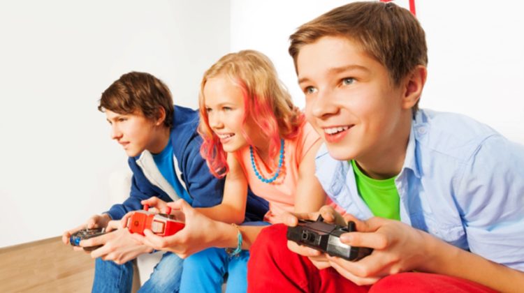 Three friends with joysticks playing game console sitting on the sofa at home